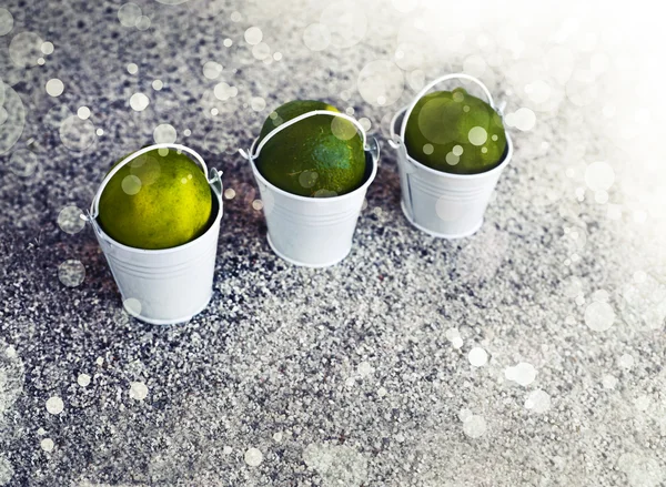 Little white buckets with limes — Stock Photo, Image