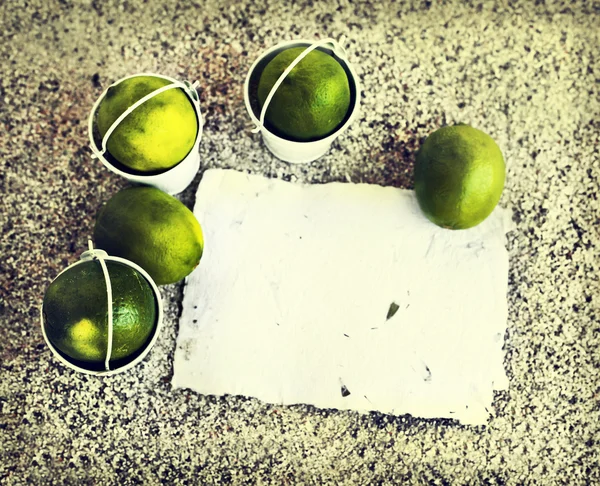 Little white buckets with limes — Stock Photo, Image