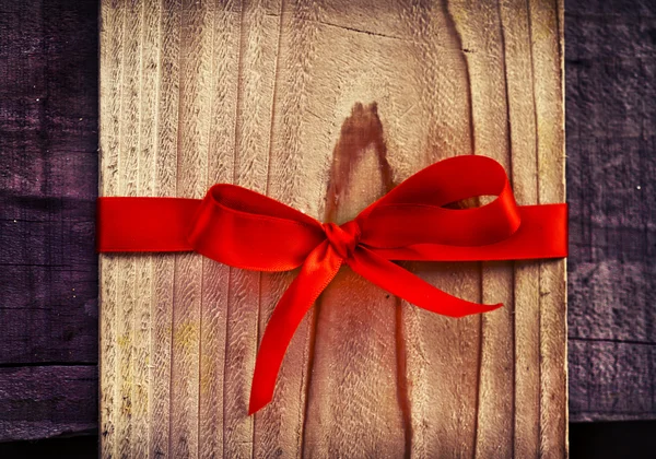 Arco rojo en regalo de madera —  Fotos de Stock