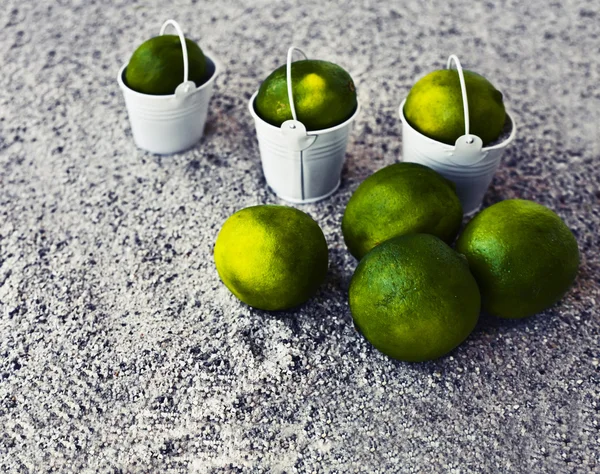 Little white buckets with limes — Stock Photo, Image