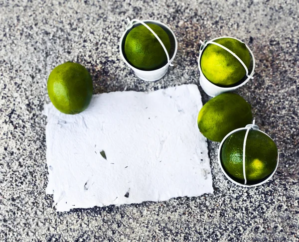 Little white buckets with limes — Stock Photo, Image