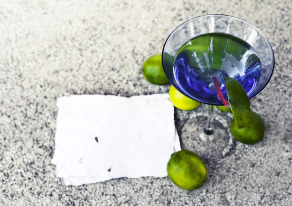Cocktail glass with straw and limes — Stock Photo, Image