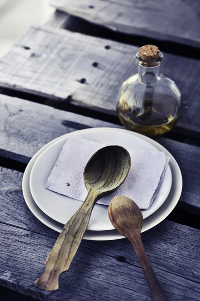 Wooden spoons, oil and plates — Stock Photo, Image