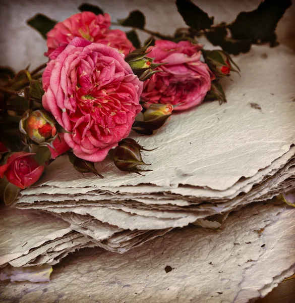 Rosas cor de rosa com papéis na mesa de madeira — Fotografia de Stock