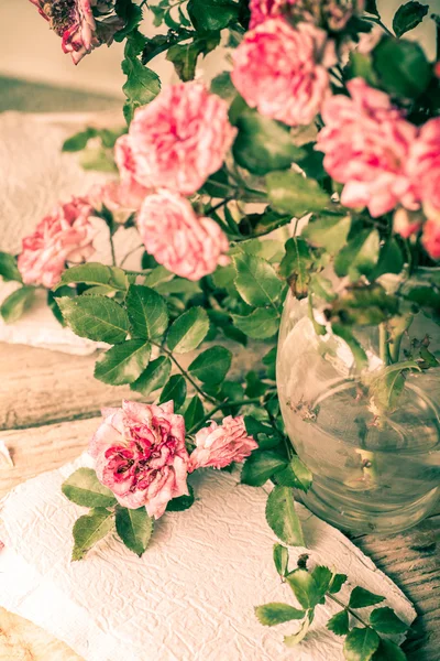 Rosas rosadas con papeles sobre mesa de madera —  Fotos de Stock