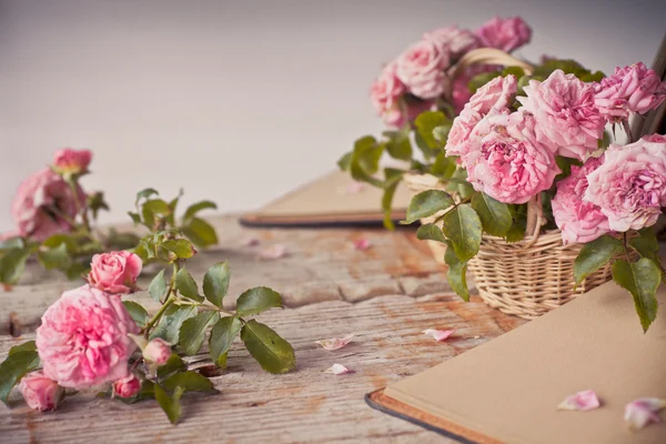 粉红玫瑰用记事本木制的桌子上 — 图库照片