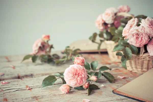 Rosas cor de rosa com bloco de notas na mesa de madeira — Fotografia de Stock