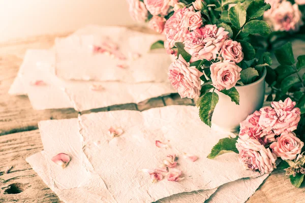 Rosas rosadas con papeles sobre mesa de madera —  Fotos de Stock