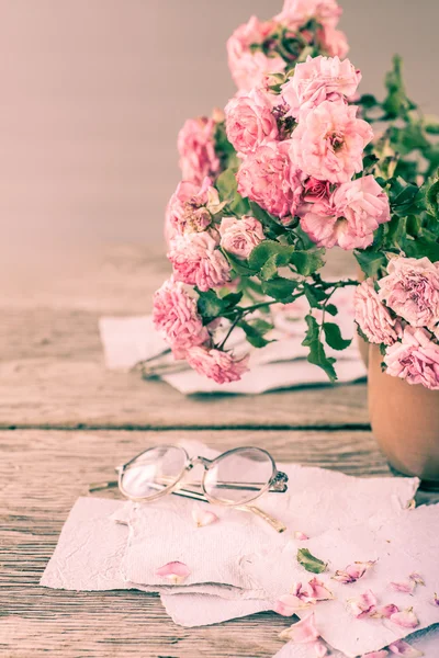 Rosas rosadas con gafas sobre mesa de madera — Foto de Stock