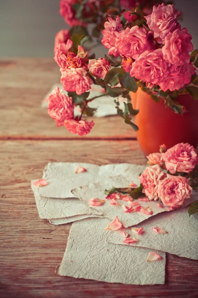 Rosas rosadas con papeles sobre mesa de madera — Foto de Stock