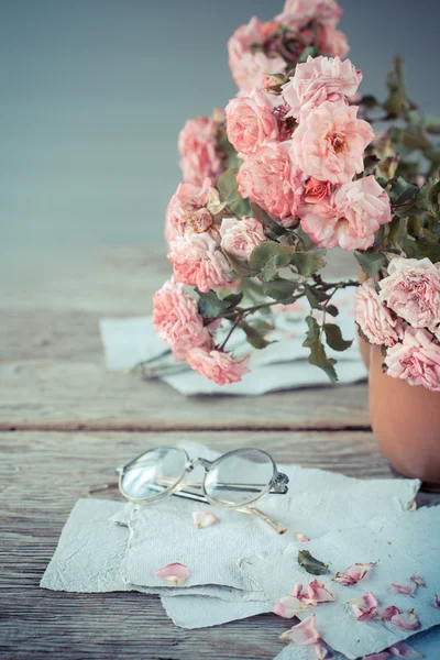 Rosas rosadas con gafas sobre mesa de madera — Foto de Stock