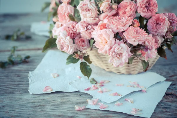 Rózsaszín rózsák papírokat fából készült asztal — Stock Fotó