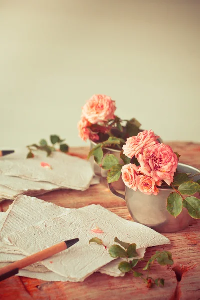 Rózsaszín rózsák papírokat fából készült asztal — Stock Fotó