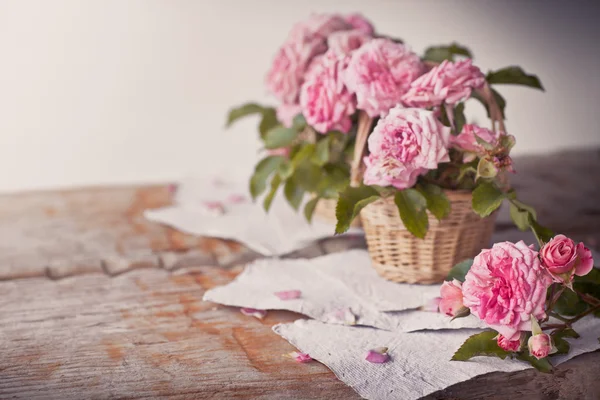 Roze rozen met papieren op houten tafel — Stockfoto