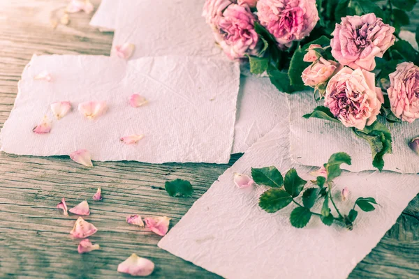 Rosas rosadas con papeles sobre mesa de madera — Foto de Stock