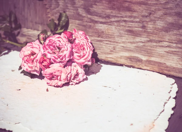 Rosas cor de rosa com papéis na mesa de madeira — Fotografia de Stock