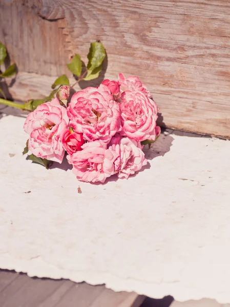 Pink roses with papers on wooden table — Stock Photo, Image