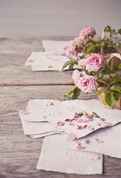 Rosas cor de rosa com papéis na mesa de madeira — Fotografia de Stock