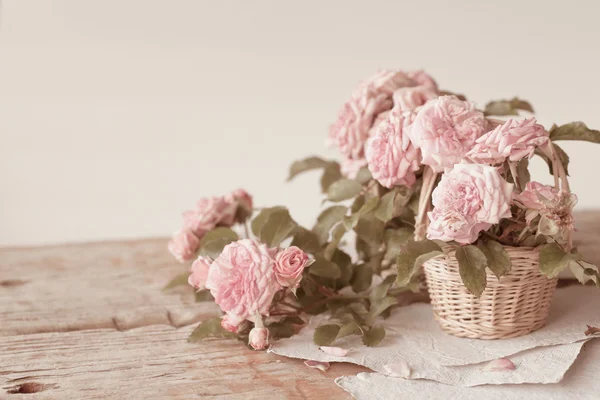 Rosa rosor med papper på träbord — Stockfoto