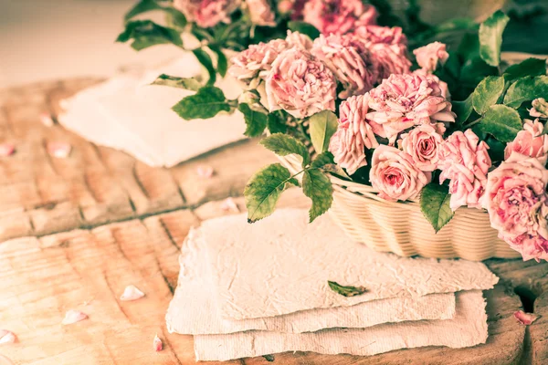 Rosa Rosen mit Papieren auf Holztisch — Stockfoto