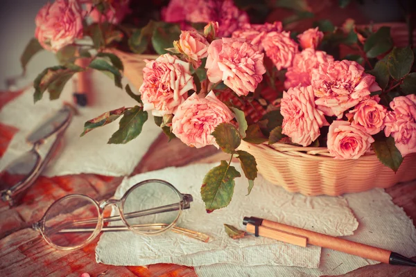 Pink roses with glasses on wooden table — Stock Photo, Image