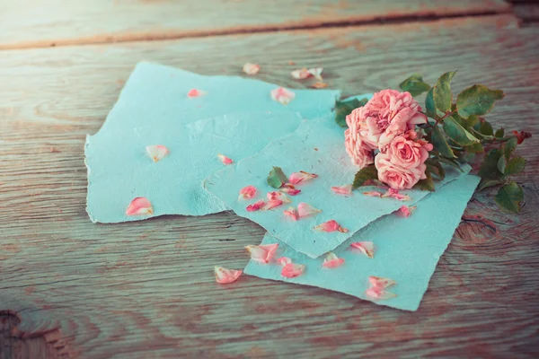 Rosas rosadas con papeles sobre mesa de madera — Foto de Stock