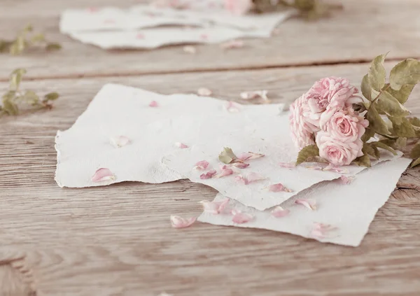 Rosas cor de rosa com papéis na mesa de madeira — Fotografia de Stock