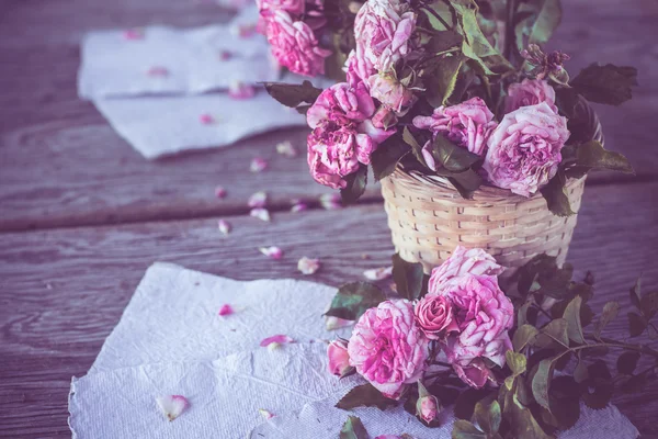 Rosas cor de rosa com papéis na mesa de madeira — Fotografia de Stock