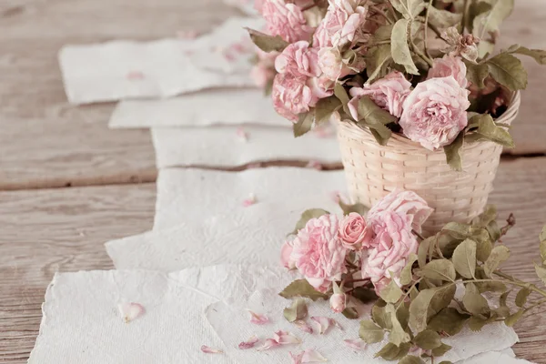 Roze rozen met papieren op houten tafel — Stockfoto