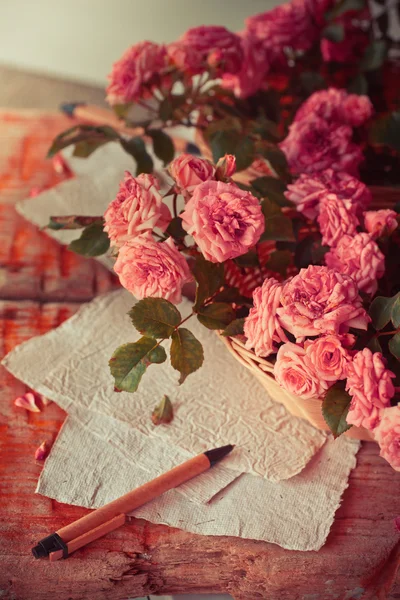 Rosas rosadas con papeles sobre mesa de madera — Foto de Stock