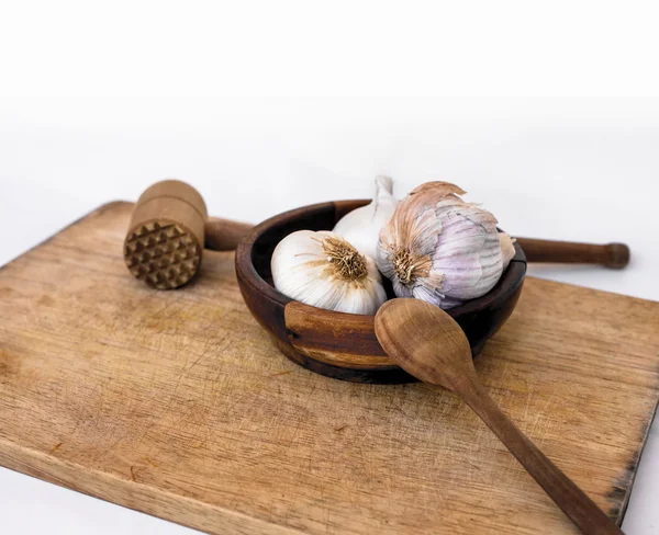 Garlic with spoon and kitchen hammer — Stock Photo, Image