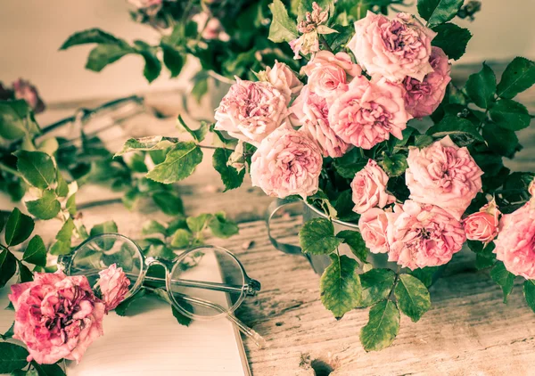 Rosas rosadas con gafas sobre mesa de madera — Foto de Stock