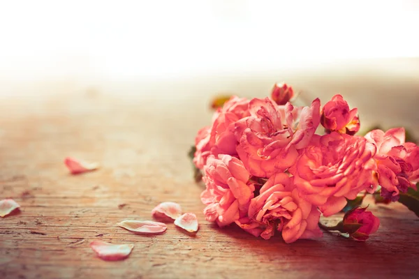 Růžové růže na dřevěný stůl — Stock fotografie