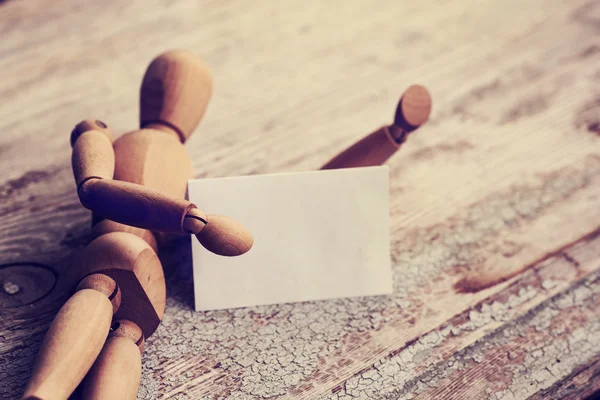 Wooden man holding white card — Stock Photo, Image