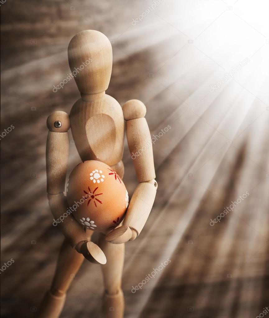 Wooden man holding easter egg