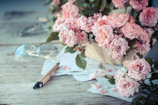 戴着眼镜木制的桌子上的粉红玫瑰 — 图库照片