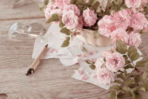 Rosas cor de rosa com óculos na mesa de madeira — Fotografia de Stock