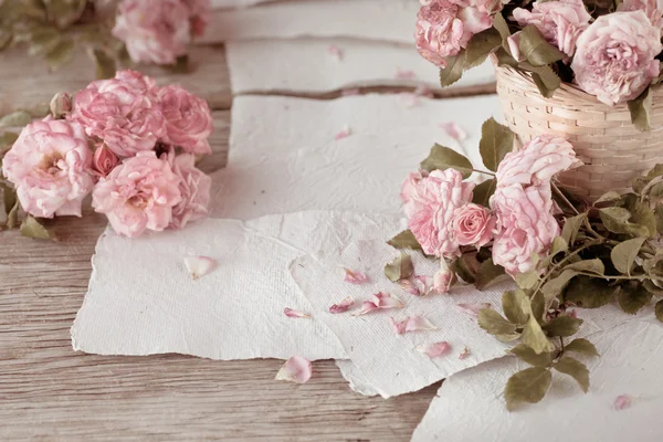 Rosas rosadas con papeles sobre mesa de madera —  Fotos de Stock