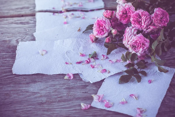 Roses roses avec papiers sur table en bois — Photo