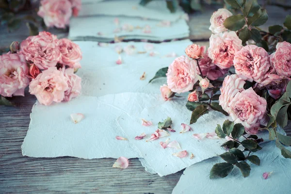 Rosas rosadas con papeles sobre mesa de madera —  Fotos de Stock