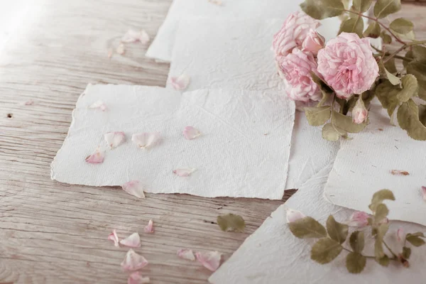 Růžové růže s papíry na dřevěný stůl — Stock fotografie