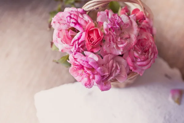 Pink roses with papers on wooden table — Stock Photo, Image