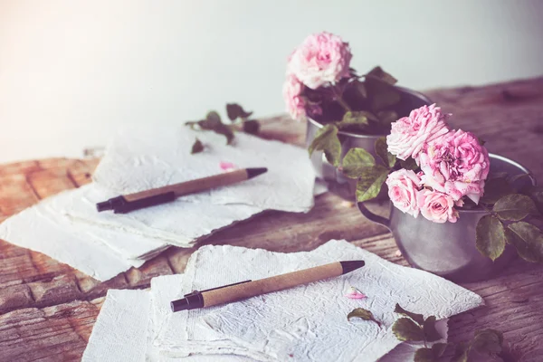 Rosen auf dem Tisch mit Stiften und Papieren — Stockfoto