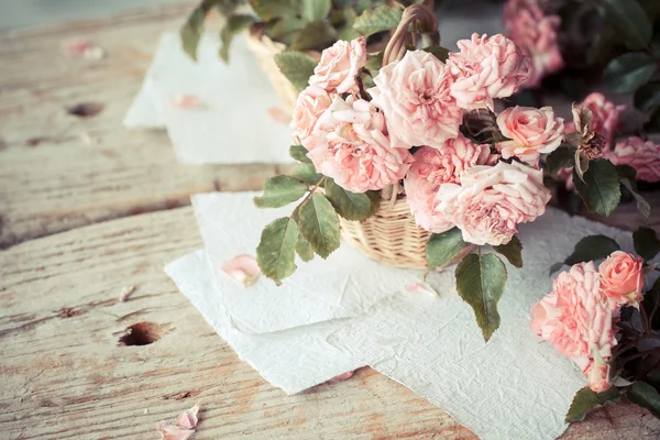 Rosa Rosen mit Papieren auf Holztisch — Stockfoto