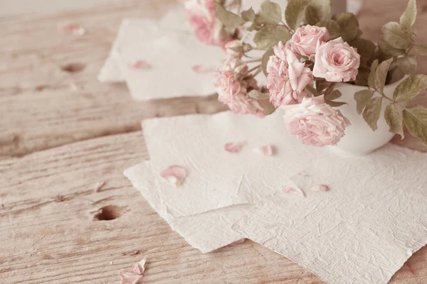 Rosas rosadas con papeles sobre mesa de madera — Foto de Stock