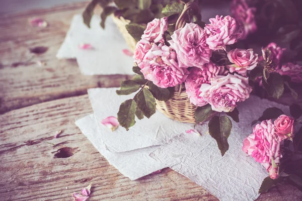 Rosas rosadas con papeles sobre mesa de madera — Foto de Stock