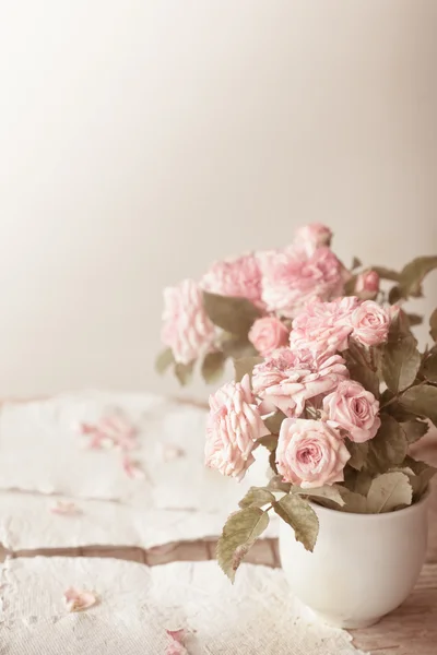 Pink roses with papers on wooden table — Stock Photo, Image