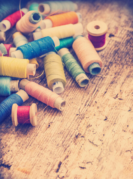 Bobbins with colorful threads on wooden table