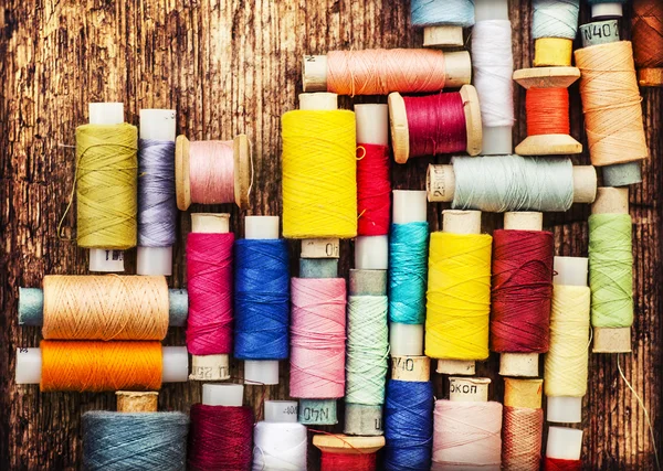 Klossen met kleurrijke draden op houten tafel — Stockfoto