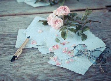 Ahşap masa gözlüklerle pembe güller